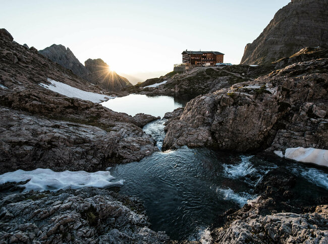 Blick auf die Karlsbaderhütte und davor der Laserzsee mit letzten Schneeresten.
