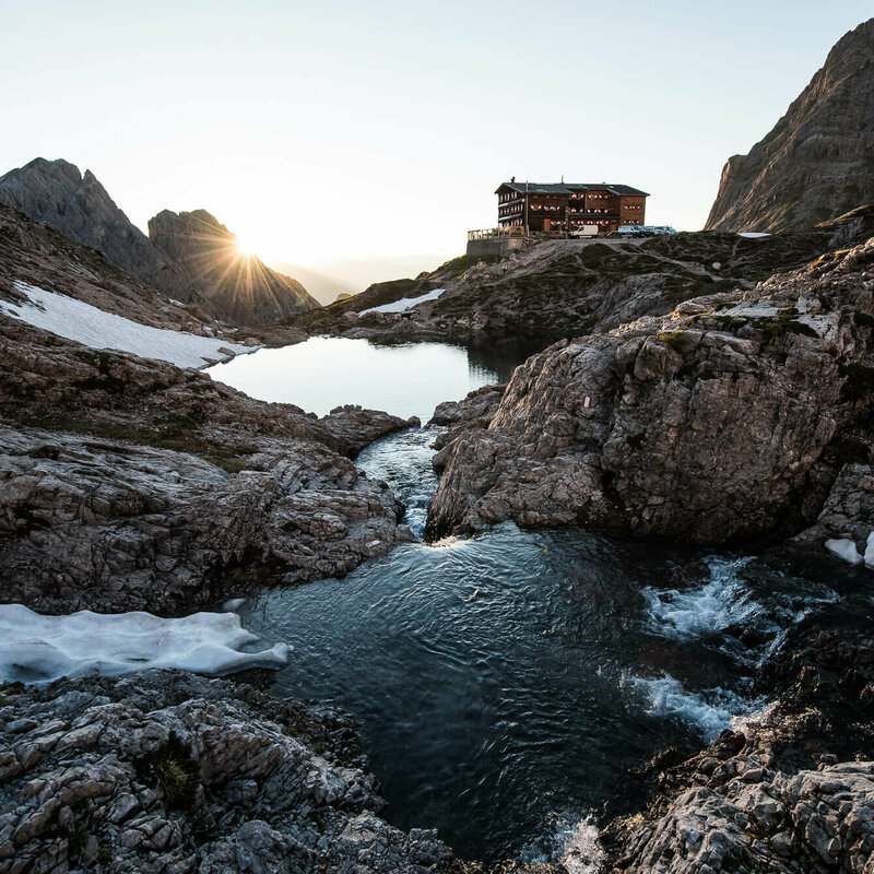 Blick auf die Karlsbaderhütte und davor der Laserzsee mit letzten Schneeresten.