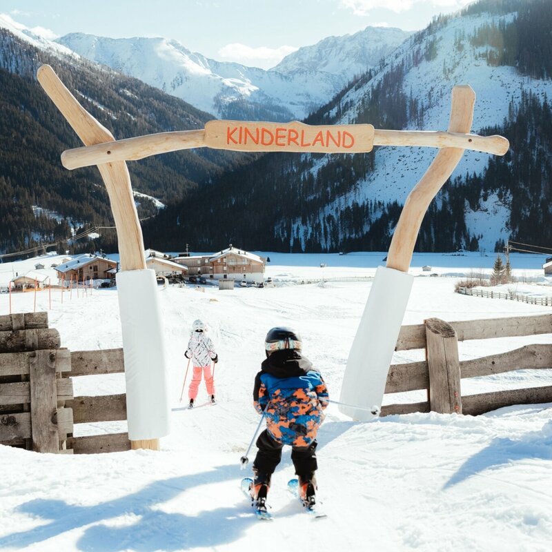 Ein Kind passiert auf Ski den Eingang ins Kinderland im Familienskigebiet Golzentipp in Obertilliach.