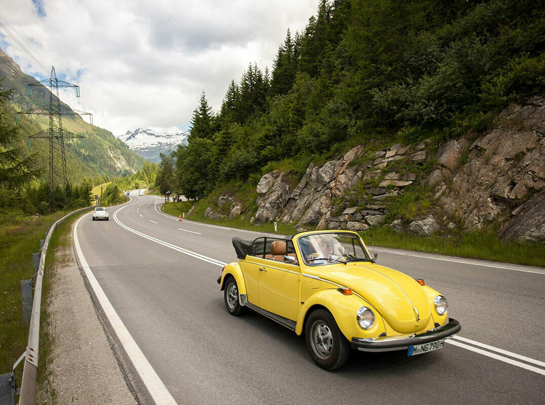 Ein gelbes Oldtimer-Cabriolet fährt auf der Felbertauernstraße, gefolgt von einem silbernen Cabriolet.