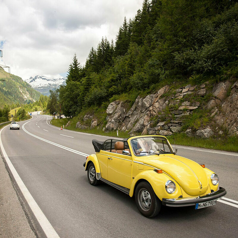 Felbertauernstraße Ein gelbes Oldtimer-Cabriolet fährt auf der Felbertauernstraße, gefolgt von einem silbernen Cabriolet.