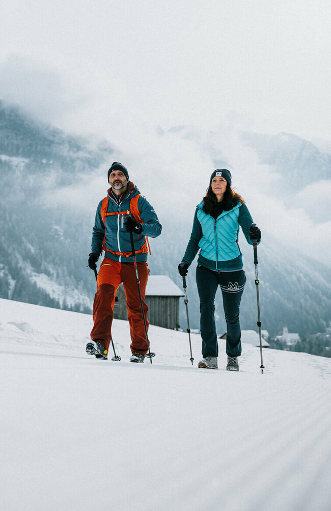 Ein Pärchen wandert auf perfekt präparierten Winterwanderwegen durch Osttirols Winterlandschaft.