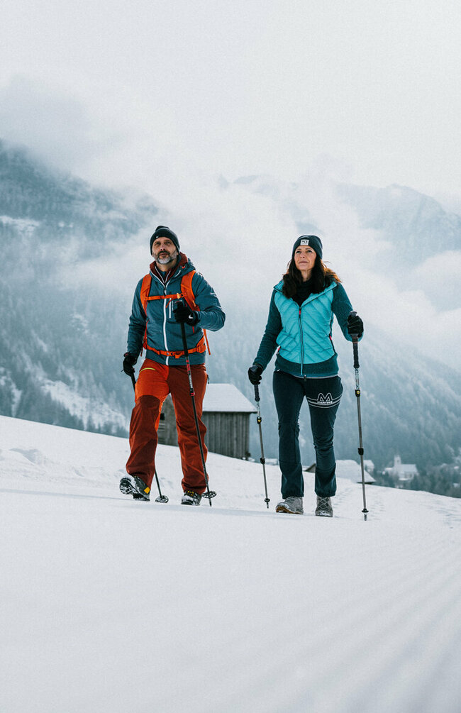 Ein Pärchen wandert auf perfekt präparierten Winterwanderwegen durch Osttirols Winterlandschaft.