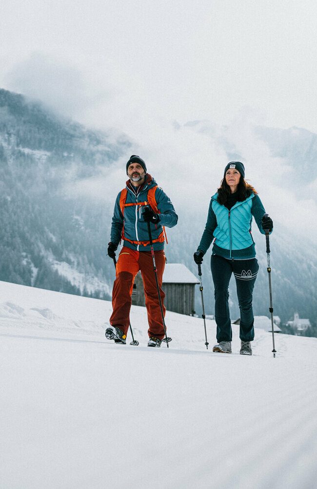 Ein Pärchen wandert auf perfekt präparierten Winterwanderwegen durch Osttirols Winterlandschaft.