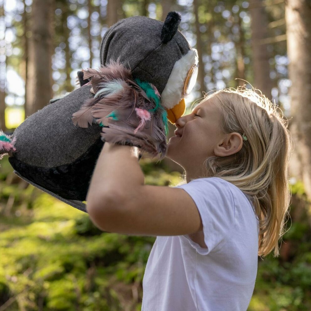 Ein Kind spielt mit Eule Elfi im Wald