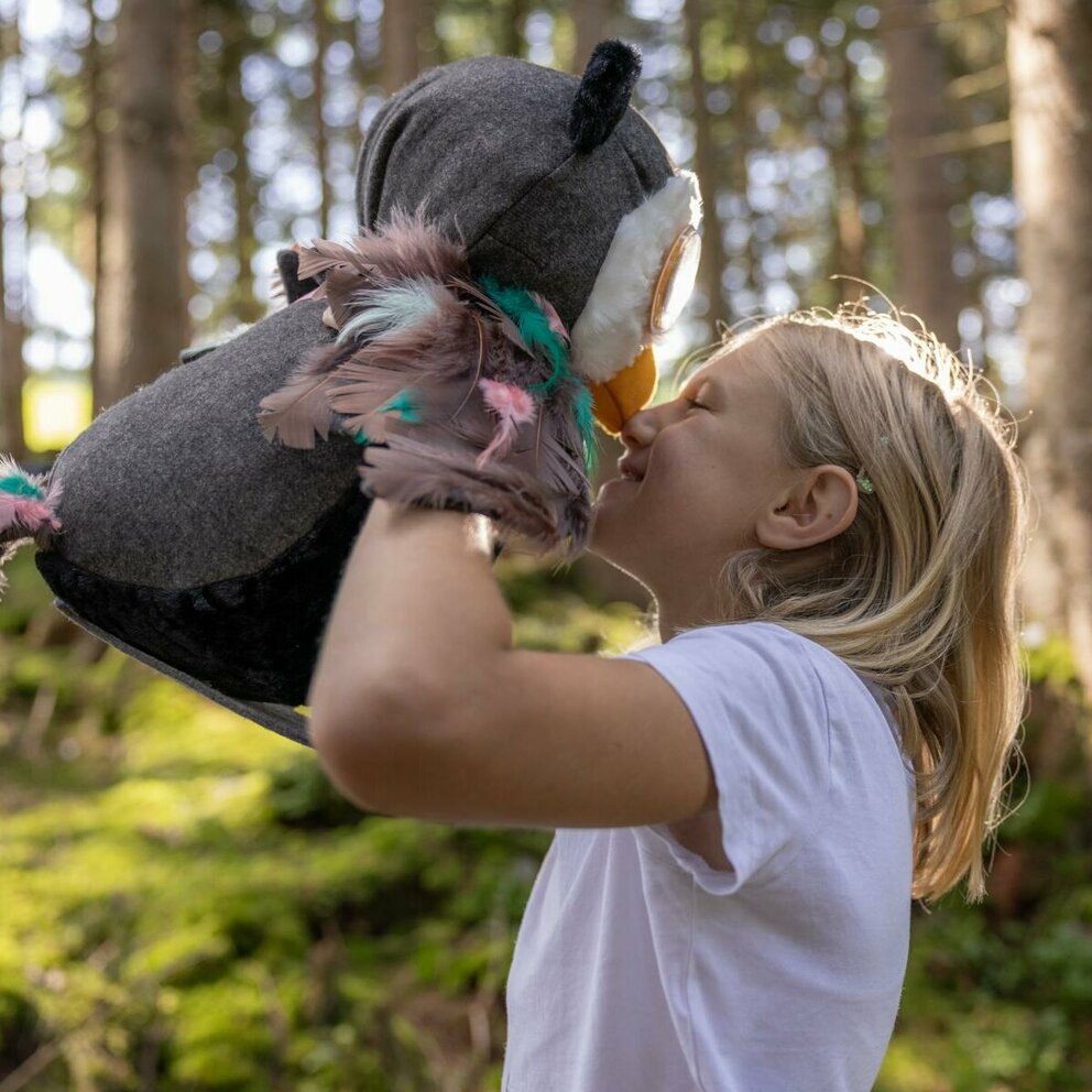 Ein Kind spielt mit Eule Elfi im Wald