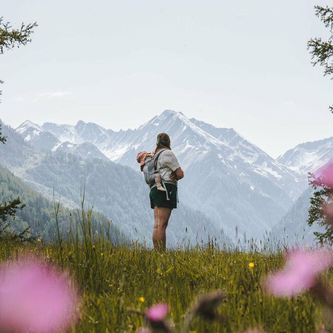 Eine Mama steht mit ihrem Kind auf einer Bergwiese in Prägraten in Osttirol.