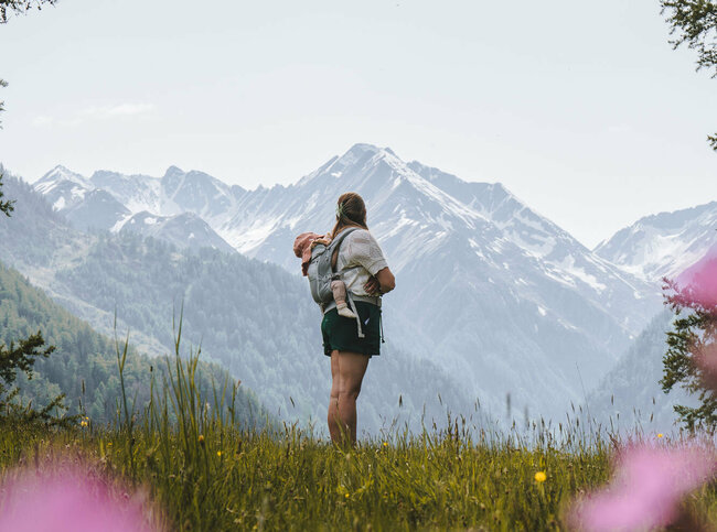 Eine Mama steht mit ihrem Kind auf einer Bergwiese in Prägraten in Osttirol.