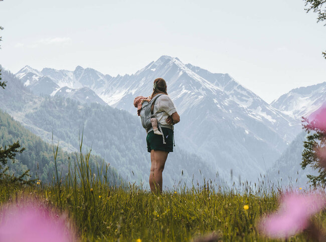 Eine Mama steht mit ihrem Kind auf einer Bergwiese in Prägraten in Osttirol.