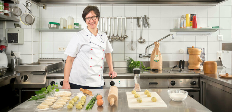 Köchin zeigt in einer Gastroküche alle wichtigen Zutaten und Verarbeitungsstufen der Produkte bis hin zu den fertigen Schlipfkrapfen