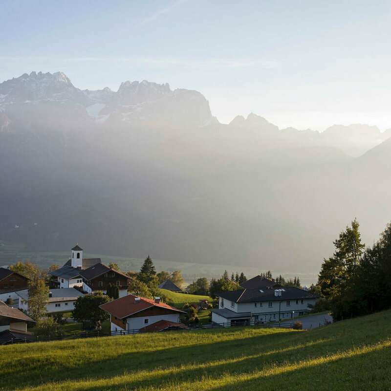 Bei Abenddämmerung am Iselsberg liegt ein leichter Dunst in der Luft. Links im Bild ist der Wallfahrtsort Lavant zu sehen mit den Kirchen St. Ulrich und St. Paul 
