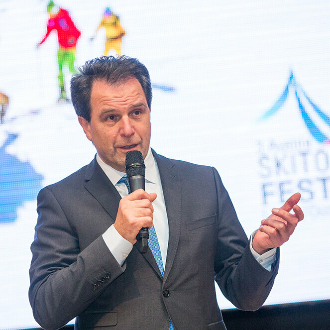 Franz Theurl im Anzug mit einem Mikrofon in der Hand.