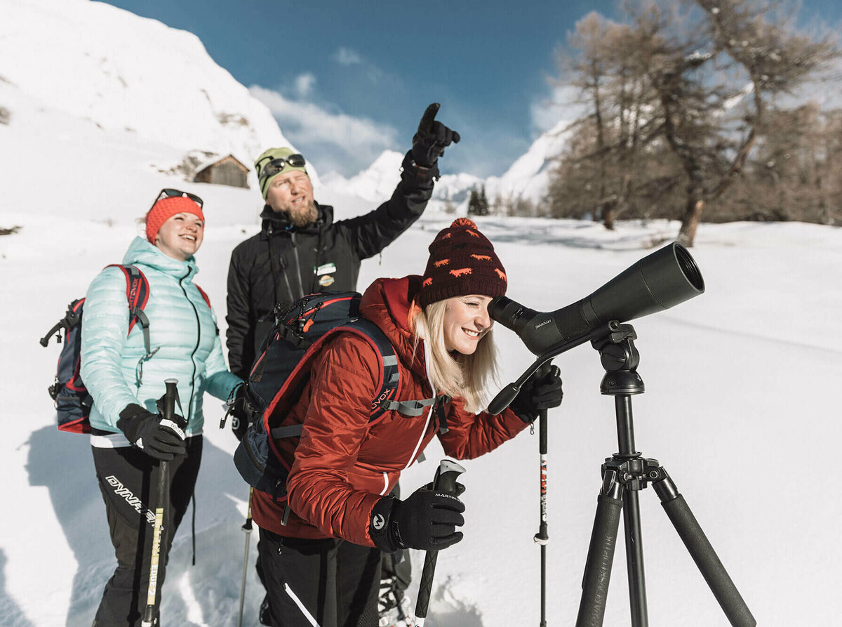 Eine Gruppe beim Schneeschuhwandern Ködnitztal, eine Frau schaut durch ein Fernglas