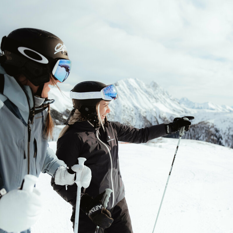 Frau zeigt in die Ferne - Skifahren in Obertilliach