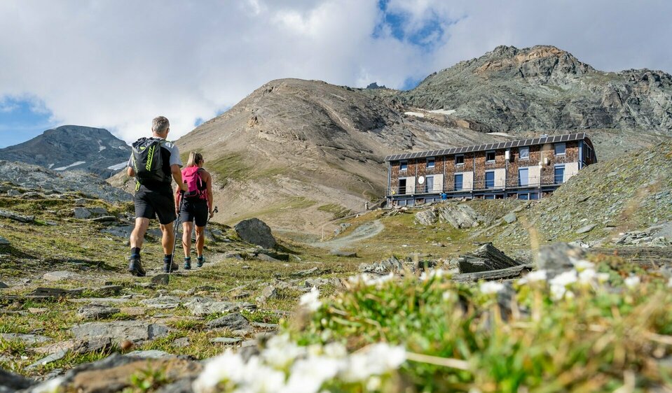 Wanderer auf Etappe 3 der Glocknerkrone in Osttirol nahe Kals am Großglockner mit Blick auf Schutzhütte und Gebirge beim Weitwandern.