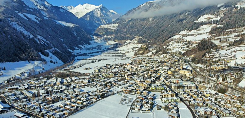 Blick von oben auf das verschneite Matrei in Osttirol an einem sonnigen Wintertag.