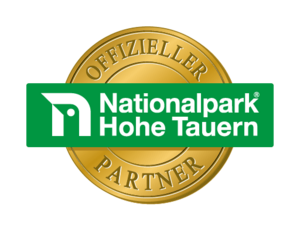 Offizielles Partner Logo des Nationalparks Hohe Tauern. Eine goldene Münze mit dem grün-weißen Nationalpark Logo.