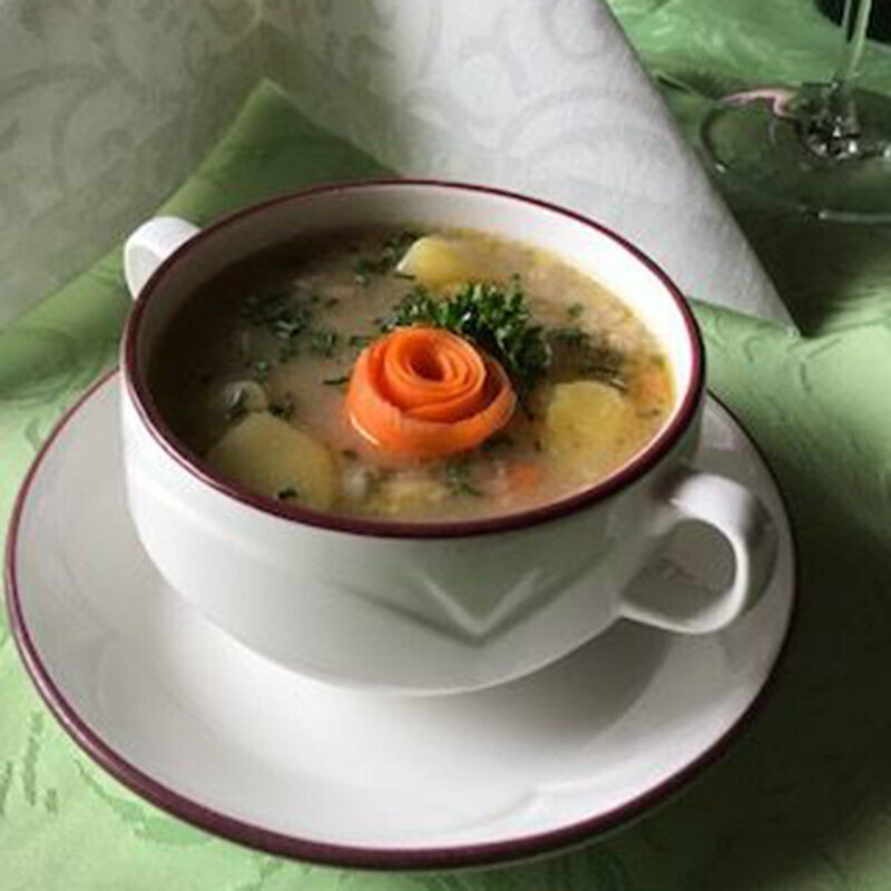 Eine Portion Erdäpfelsuppe mit einer Rose aus Karotten verziert.