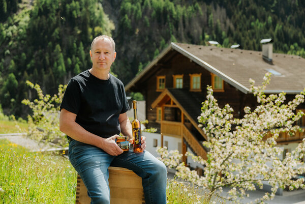 ein Mann sitzt auf einem Bienenstock vor einem Bauernhaus