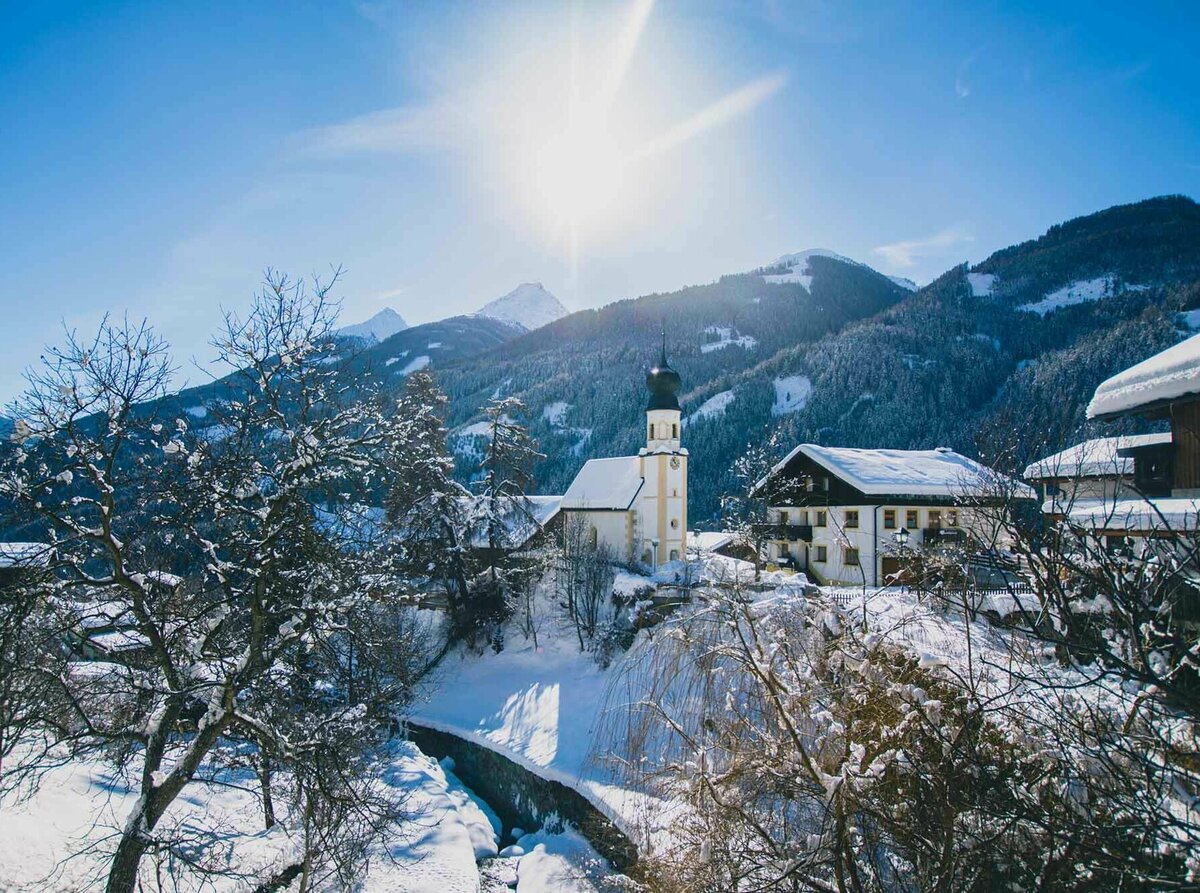 Blick auf die Kirche in Virgen im Winter bei strahlendem Sonnenschein.