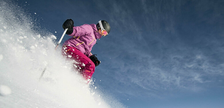 Eine pink-lila gekleidete Freeriderinn im Pulverschnee im Großglockner Resort in Kals-Matrei.