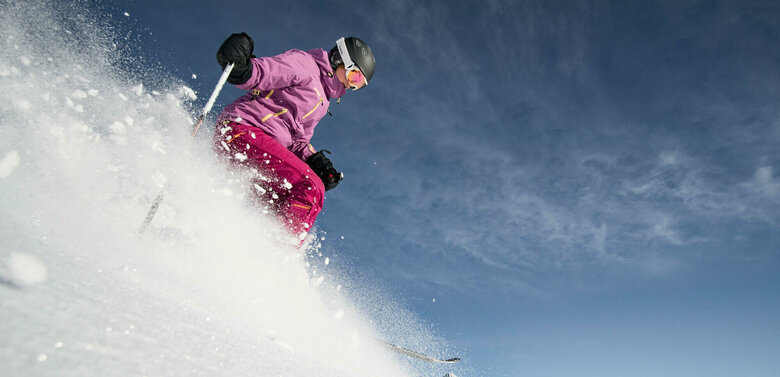 Eine pink-lila gekleidete Freeriderinn im Pulverschnee im Großglockner Resort in Kals-Matrei.