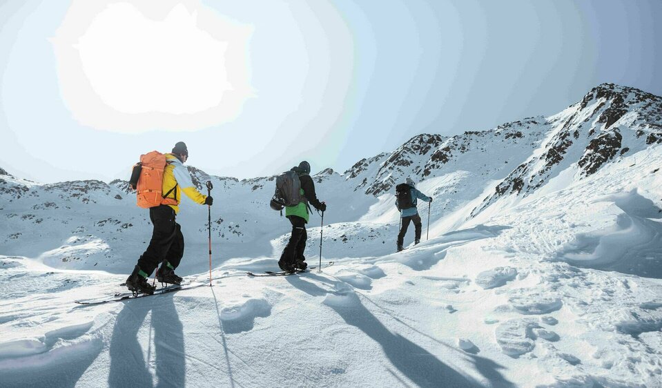 Drei Skitourengeher beim Aufstieg in einem sonnigen Hang im winterlichen Defereggental.