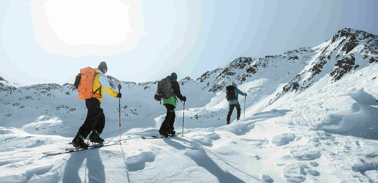 Drei Skitourengeher beim Aufstieg in einem sonnigen Hang im winterlichen Defereggental.