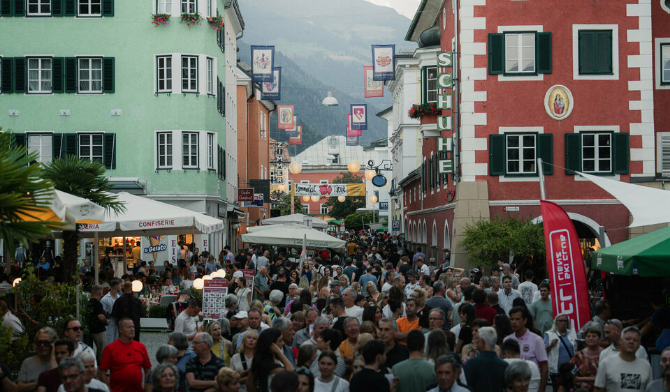 Zu sehen ist der Hauptplatz mit Bilck auf die Gasse zum Johannesplatz. Unzählige Menschen sind unterwegs.
