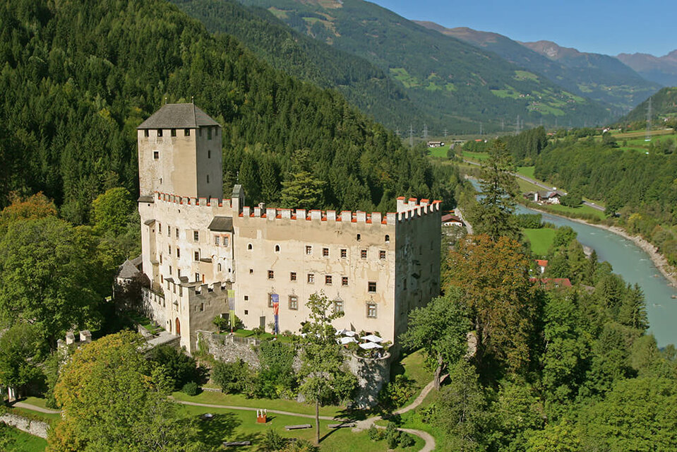 Sommerliche Ansicht des Schlosses Bruck mit dem Iselfluss im Hintergrund