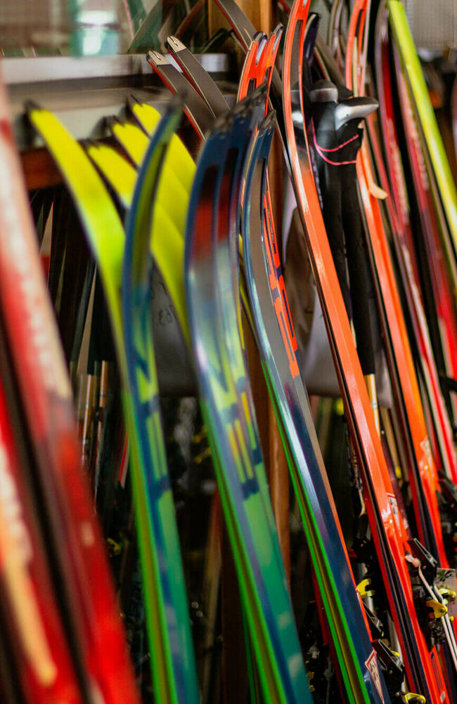 Verschiedene Ski stehen nebeneinander angelehnt an einen Ständer.