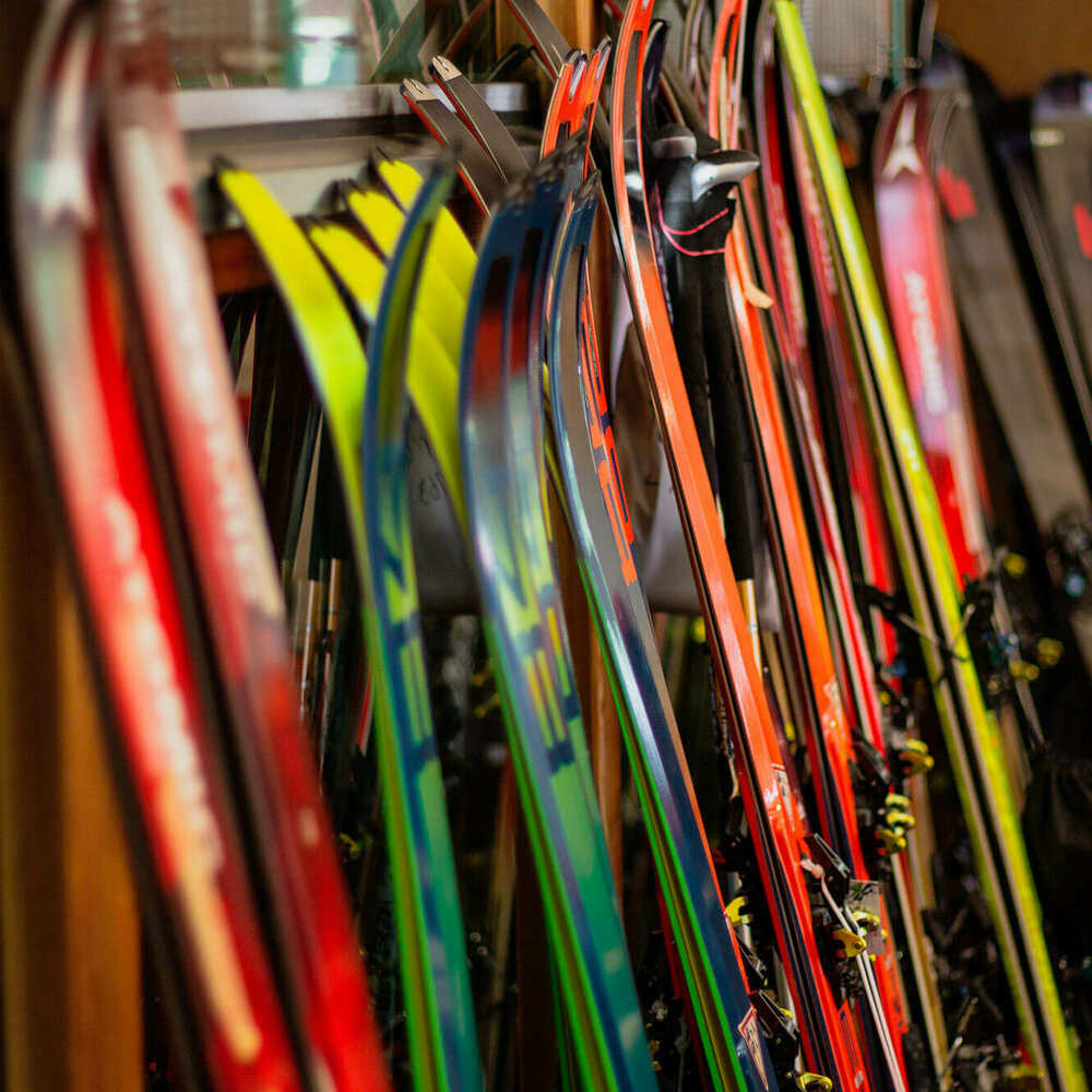 Verschiedene Ski stehen nebeneinander angelehnt an einen Ständer.