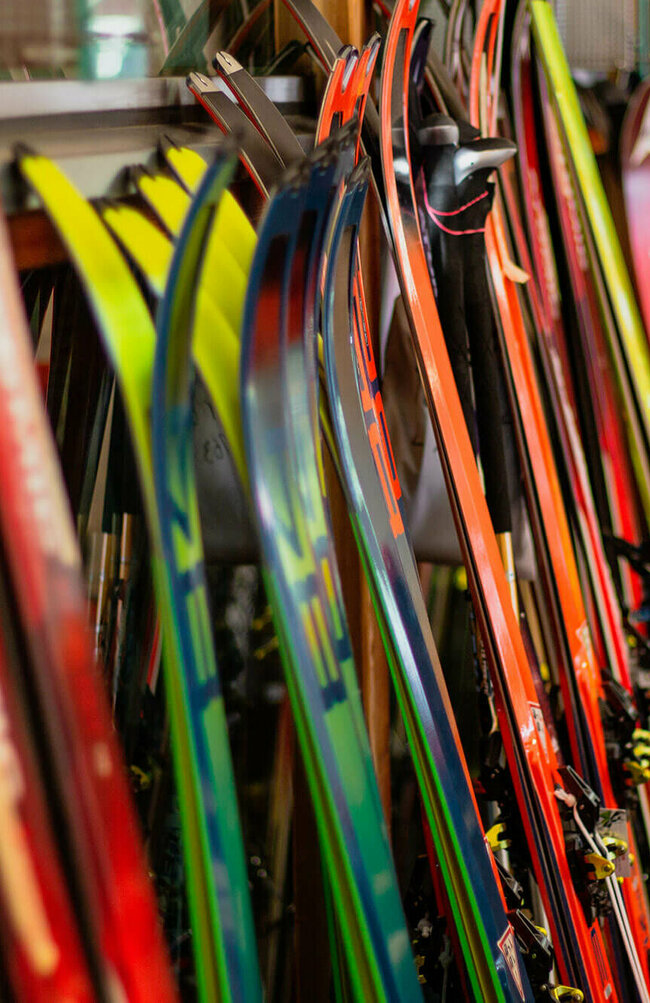 Verschiedene Ski stehen nebeneinander angelehnt an einen Ständer.
