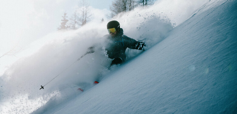 Ein Skitourenfahrer bei der Abfahrt von der Roten Wand im Defereggental. Er fährt durch Tiefschnee und Trägt Helm, Skibrille und Stöcke. 