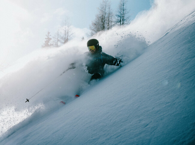 Abfahrten vom Allerfeinsten erwarten dich auf Osttirols Skitourenrouten. Ein Skitourenfahrer bei der Abfahrt von der Roten Wand im Defereggental. Er fährt durch Tiefschnee und Trägt Helm, Skibrille und Stöcke.