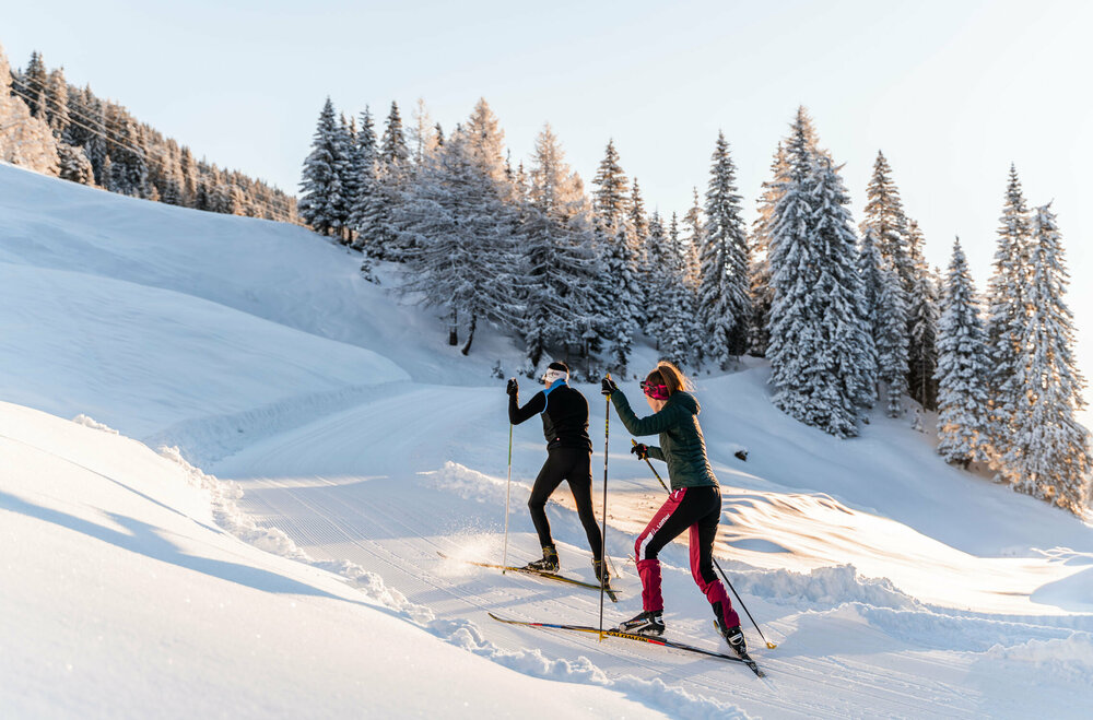 Langlaufen in Rauchenbach Zwei Langläufer:innen auf der Langlaufloipe in Kartitsch bergauf zur Höhenloipe und dem Dorfberg.