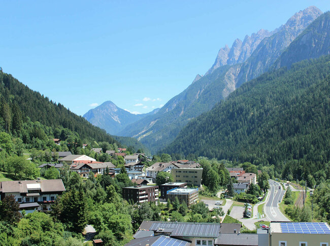 Ortsansicht von Thal mit den umliegenden Wäldern und Bergen im Hochsommer.