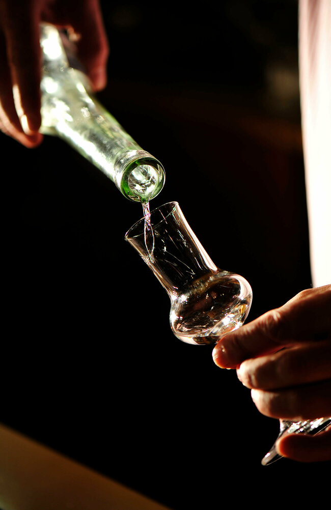 Osttiroler Pregler wird aus der Flasche in ein Schnapsglas eingeschenkt.