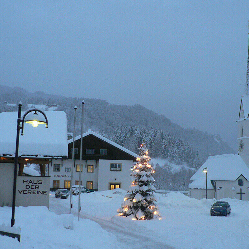 Das tief eingeschneite Dorf Schlaiten mit beleuchtetem Tannenbaum vor der Kirche.
