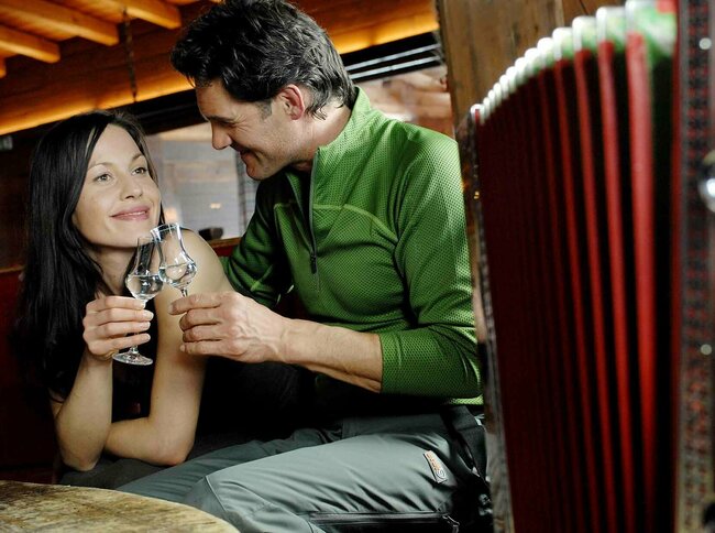 Ein Pärchen stoßt mit einem Osttiroler Pregler an und Vordergrund eine Ziehharmonika für ein authentisches Bild..